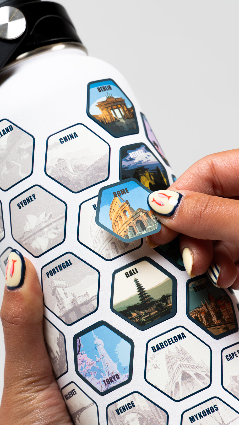 Person placing a sticker on a water bottle with travel-themed designs.
